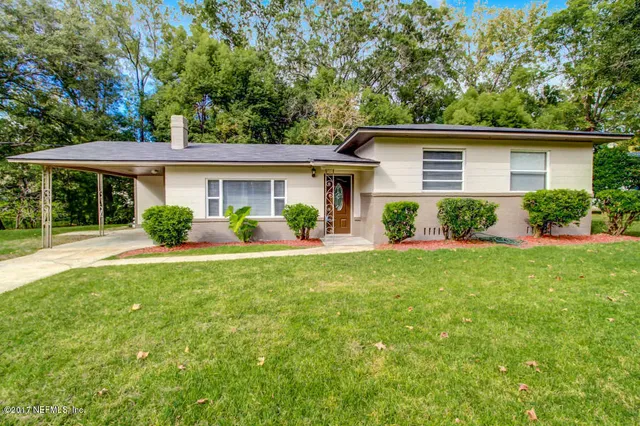 a view of house with a yard and potted plants