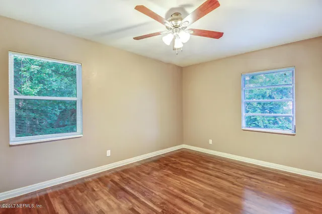 a view of an empty room with wooden floor and a window