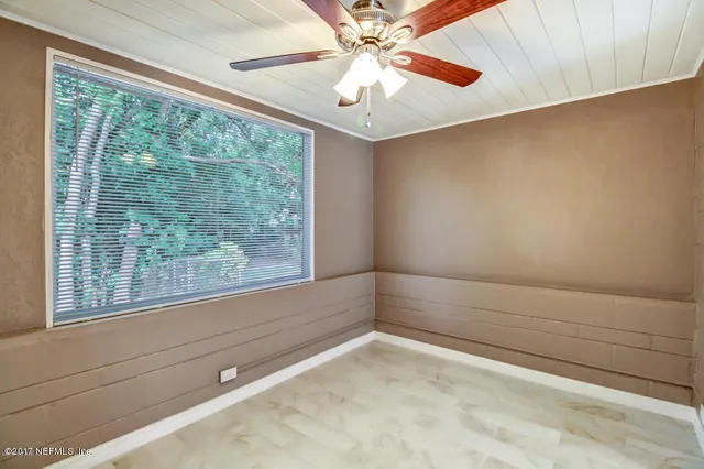 a view of empty room with window and ceiling fan