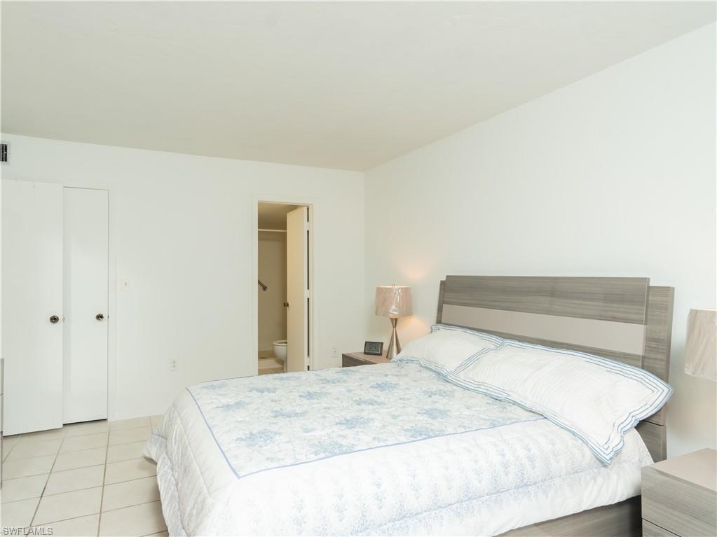 499 Forest Lakes Boulevard, Unit 2309 Naples, FL 34105 - Photo 15 of 29 a bedroom with a bed and a mirror