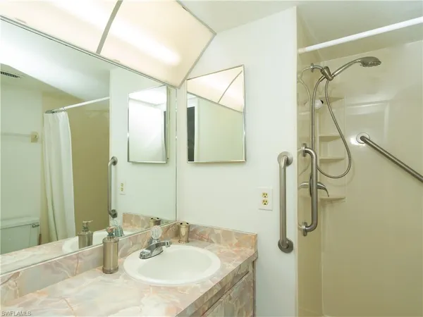 a bathroom with a granite countertop shower sink vanity and mirror