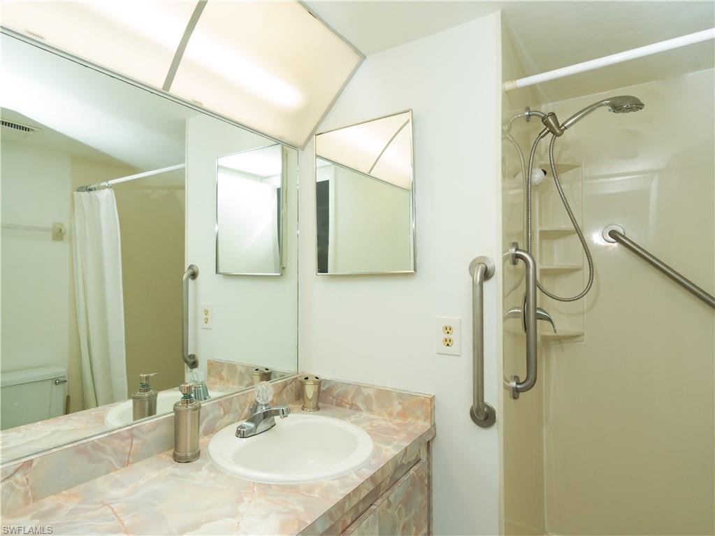 499 Forest Lakes Boulevard, Unit 2309 Naples, FL 34105 - Photo 27 of 29 a bathroom with a granite countertop shower sink vanity and mirror