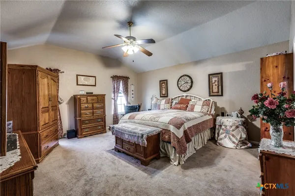 a bedroom with a large bed a flat tv screen and dresser
