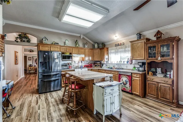 a open kitchen with stainless steel appliances granite countertop a stove dining table chairs cabinets and a sink