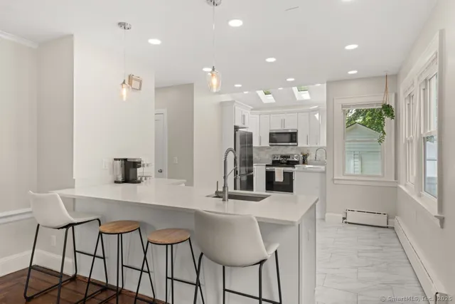 a kitchen with stainless steel appliances kitchen island granite countertop a table and chairs in it