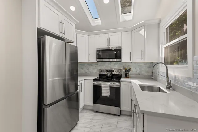 a kitchen with stainless steel appliances granite countertop a refrigerator stove microwave and sink