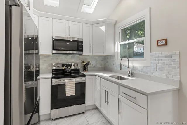 a kitchen with white cabinets stainless steel appliances and sink