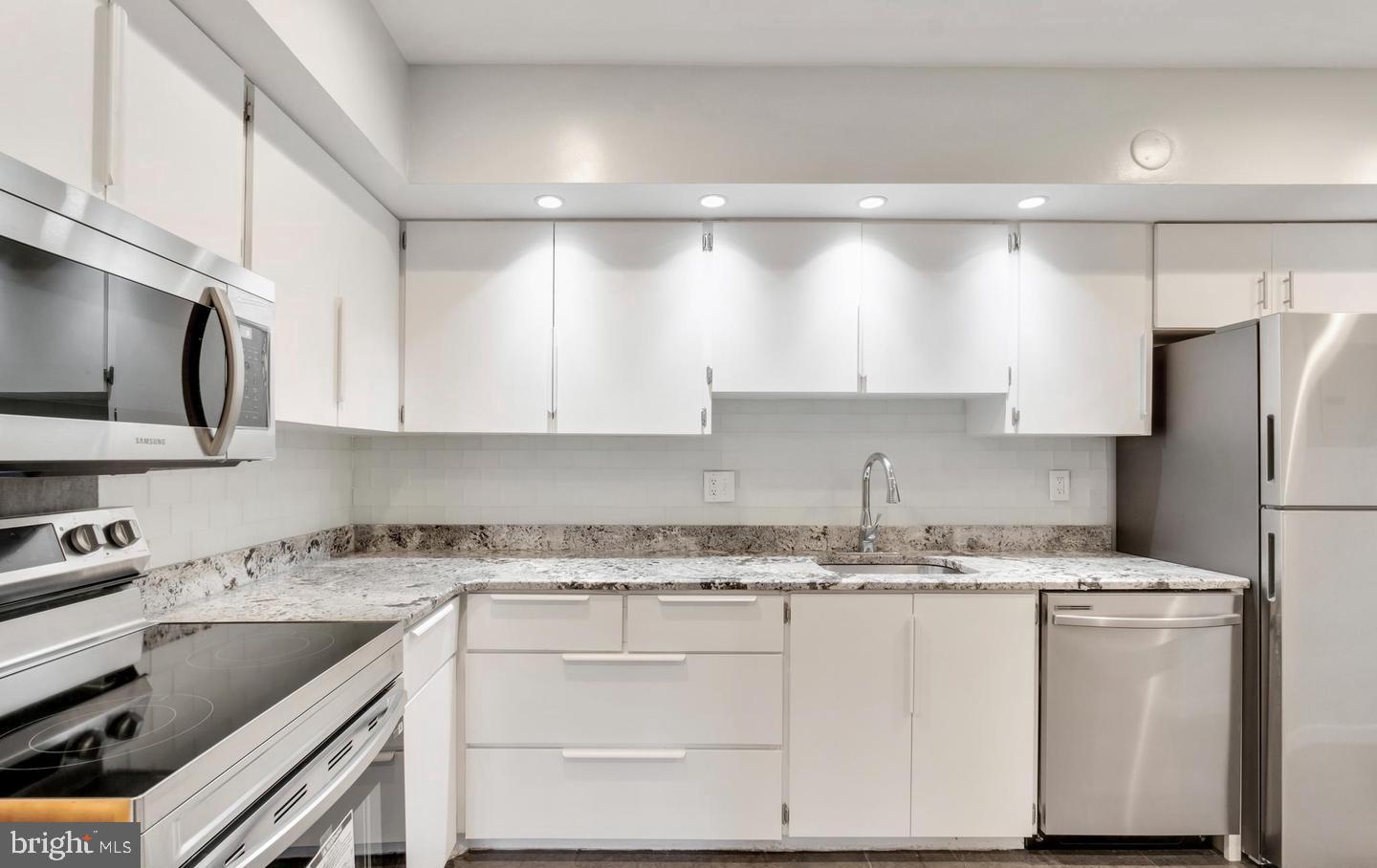 33 Stonehenge Circle, Unit 11 Baltimore, MD 21208 - Photo 10 of 22 a kitchen with kitchen island granite countertop white cabinets white stainless steel appliances and sink