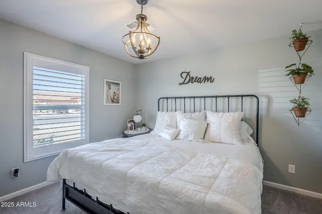 a large bed sitting in a bedroom next to a window and a chandelier