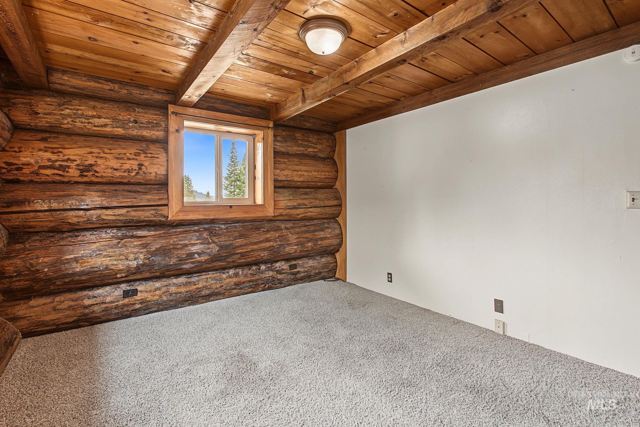 2926 Wells Bench Road Orofino, ID 83544 - Photo 26 of 48 Exposed log wall construction, natural wood ceiling, wood window frame, and plush light-toned carpeting