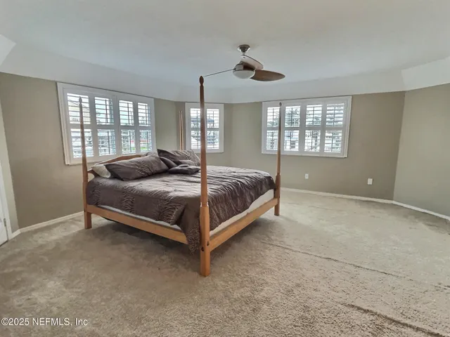 a spacious bedroom with a bed and large windows