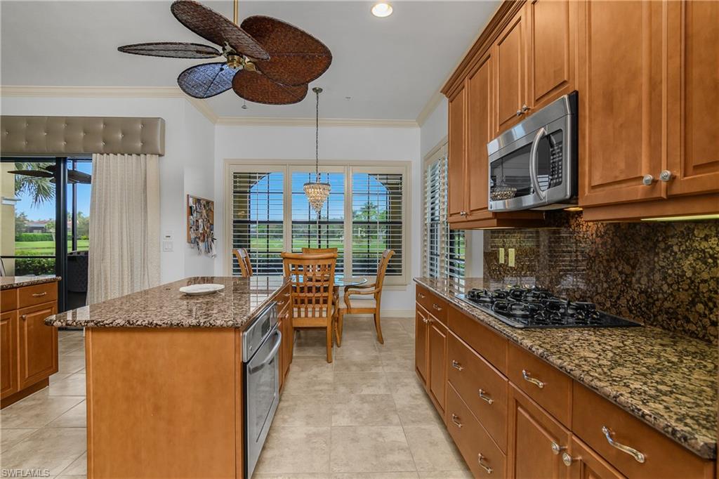 9109 Prima Way, Unit 102 Naples, FL 34113 - Photo 12 of 50 a kitchen with stainless steel appliances granite countertop a sink a stove and a wooden cabinets