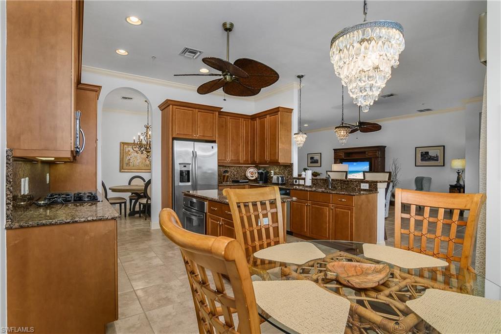 9109 Prima Way, Unit 102 Naples, FL 34113 - Photo 15 of 50 a kitchen with stainless steel appliances granite countertop a stove top oven a sink a dining table and chairs with wooden floor