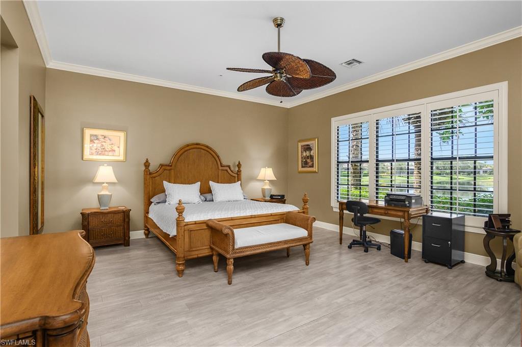 9109 Prima Way, Unit 102 Naples, FL 34113 - Photo 19 of 50 a spacious bedroom with a bed and a chandelier