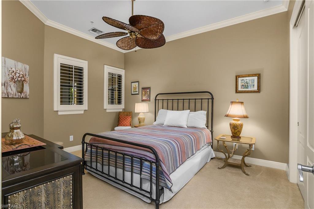 9109 Prima Way, Unit 102 Naples, FL 34113 - Photo 23 of 50 a bedroom with a bed and a chandelier