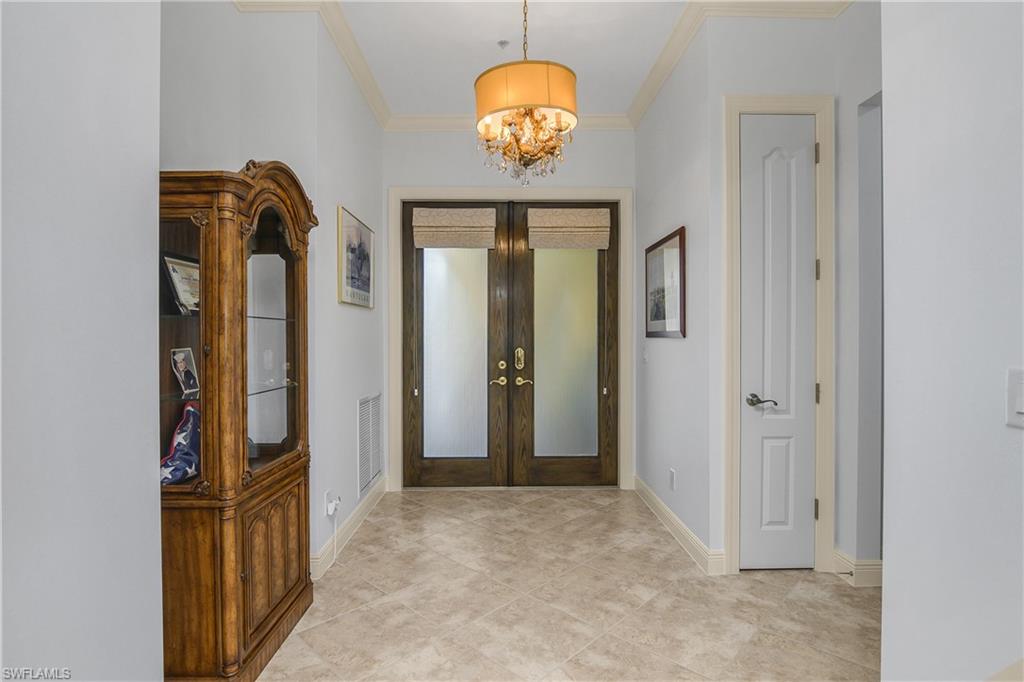 9109 Prima Way, Unit 102 Naples, FL 34113 - Photo 28 of 50 a view of a hallway with wooden floor and chandelier