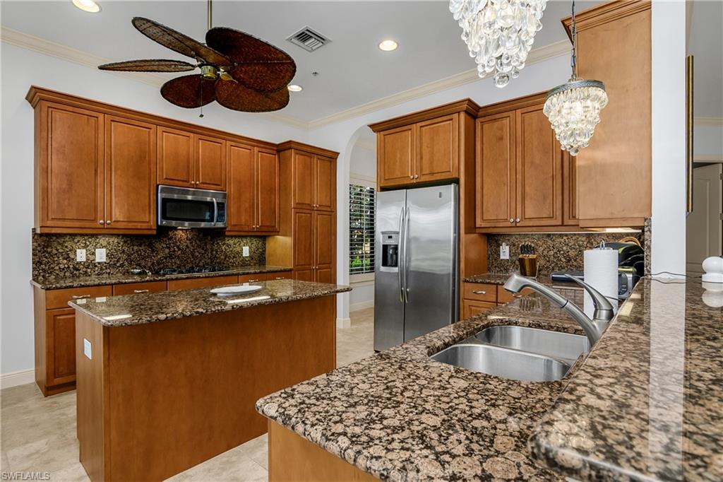 9109 Prima Way, Unit 102 Naples, FL 34113 - Photo 9 of 50 a kitchen with stainless steel appliances granite countertop a sink refrigerator stove and microwave
