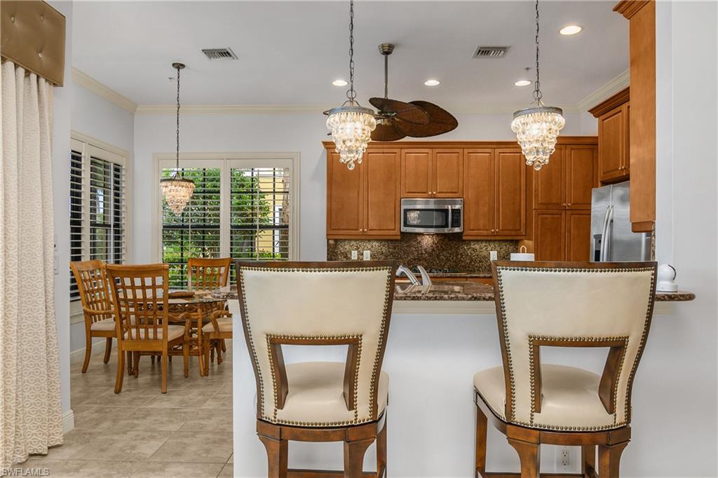 9109 Prima Way, Unit 102 Naples, FL 34113 - Photo 10 of 50 a dining room filled chandelier and kitchen view