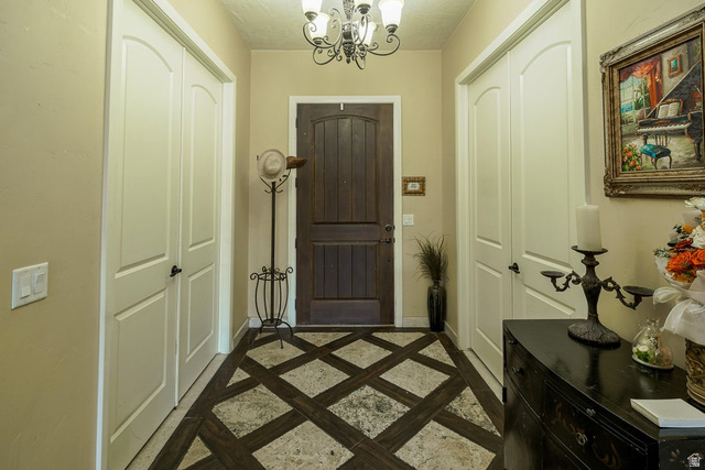 3683 South 2640 West St. George, UT 84790 - Photo 25 of 41 Entryway featuring patterned tile flooring, a dark wood-paneled door, and a decorative chandelier