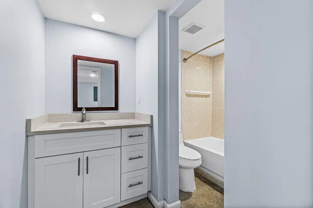a bathroom with a granite countertop sink a toilet and a mirror
