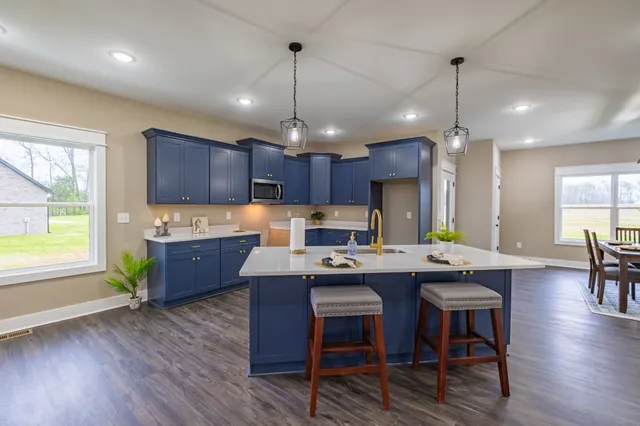 a kitchen with kitchen island granite countertop a sink cabinets and wooden floor