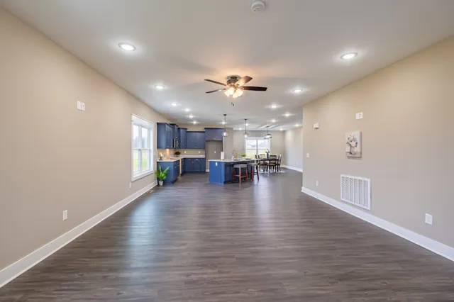 a view of a big room with wooden floor and a kitchen