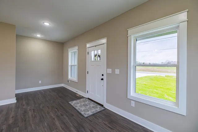 a kitchen with stainless steel appliances granite countertop wooden floors stove a refrigerator a sink dishwasher a dining table and chairs with wooden floor