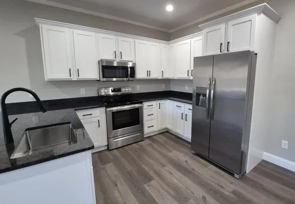 a kitchen with granite countertop a sink stove and refrigerator
