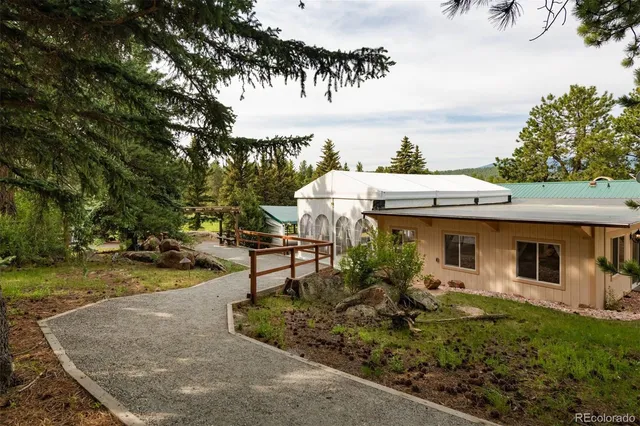 a view of a patio with table and chairs potted plants and large tree