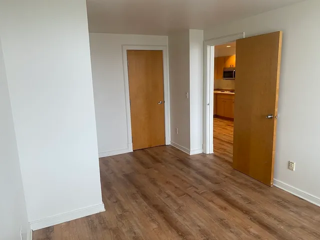 a view of an empty room with wooden floor and closet