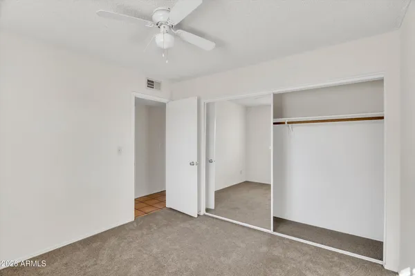 an empty room with closet and a ceiling fan