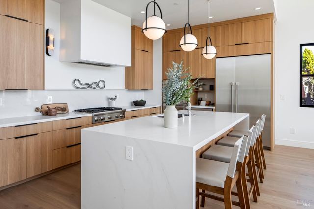 a kitchen with stainless steel appliances kitchen island granite countertop a dining table chairs and white cabinets