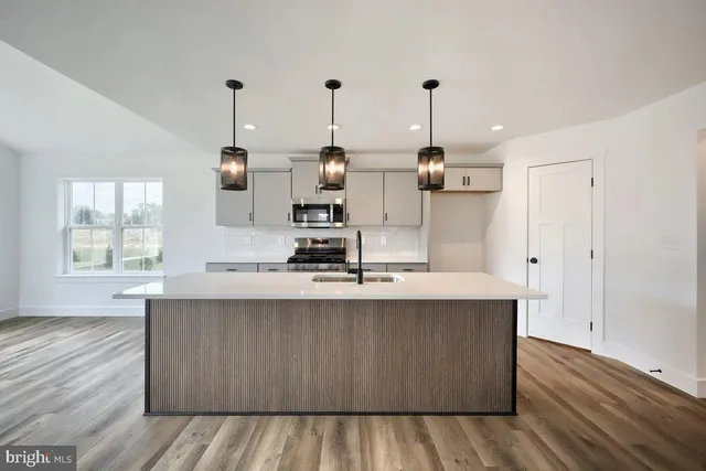 a kitchen with stainless steel appliances granite countertop a sink a stove and a wooden floors