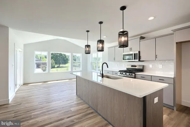 a kitchen with kitchen island a counter top space a sink stainless steel appliances and cabinets