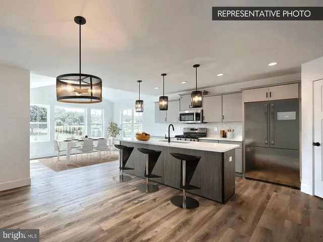 a kitchen with stainless steel appliances granite countertop a sink dishwasher a refrigerator and a dining table with wooden floor