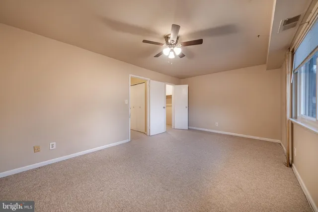 a view of an empty room with chandelier fan