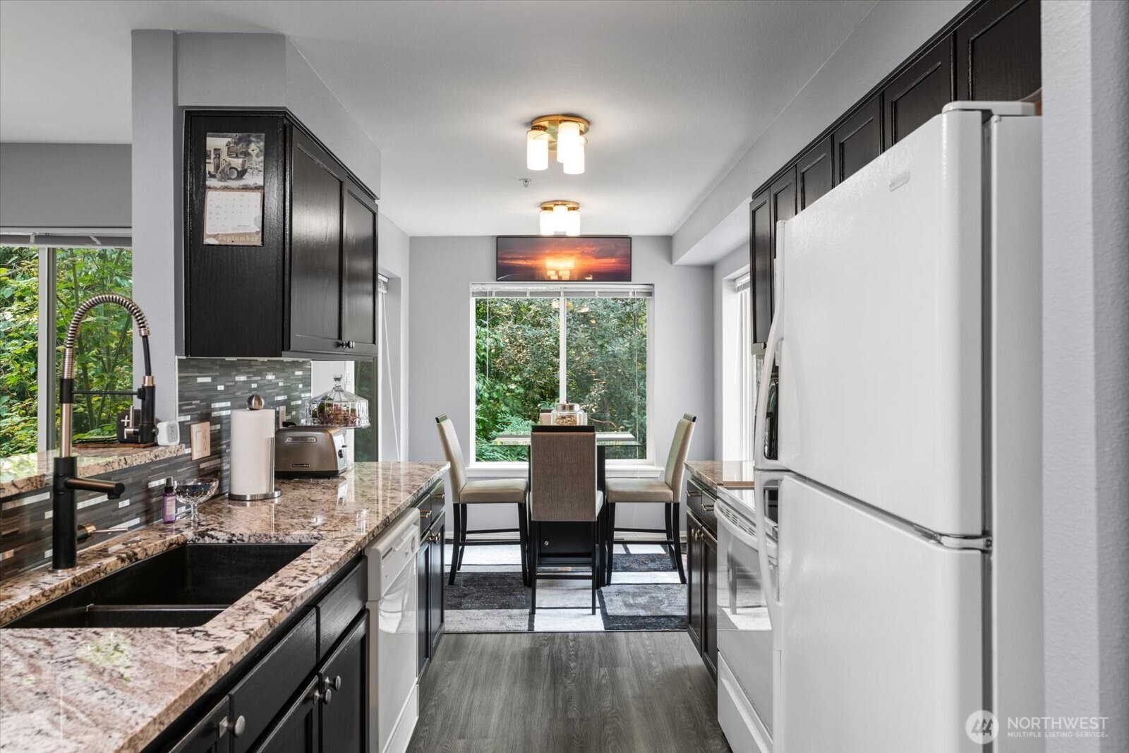723 114th Street Southwest, Unit Y203 Everett, WA 98204 - Photo 7 of 35 a kitchen with stainless steel appliances granite countertop a refrigerator a sink dishwasher a stove and white countertops with wooden floor