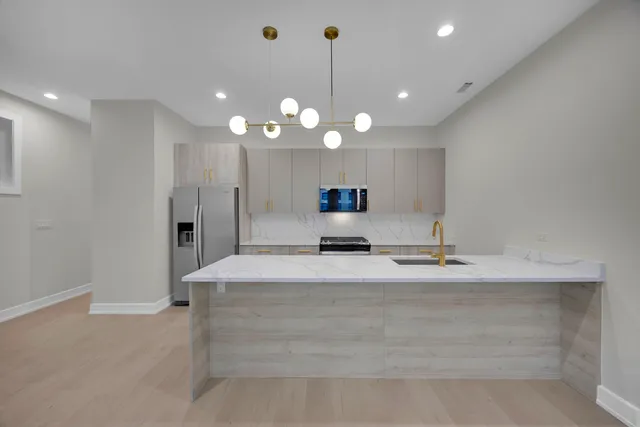 a large kitchen with kitchen island a sink stainless steel appliances and a fireplace