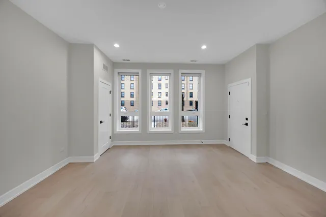 a view of an empty room with a window and wooden floor