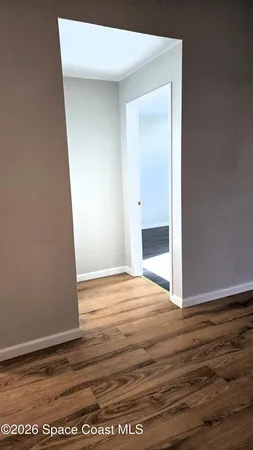 a view of an empty room with wooden floor and closet