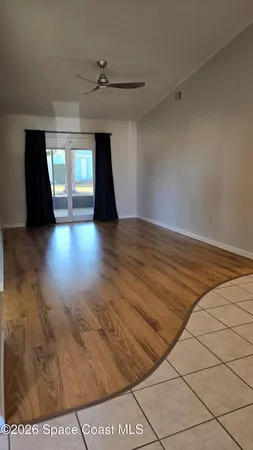 a view of empty room with wooden floor and fan