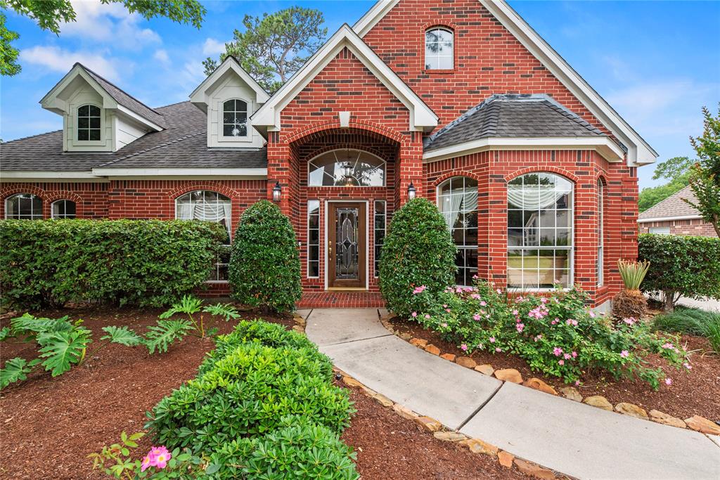 Welcome home to 18815 Mountain Shade Dr in the Thicket at Cypresswood community. The combination of a professionally landscaped pathway and transom windows framing the front door creates a welcoming and elegant entrance.