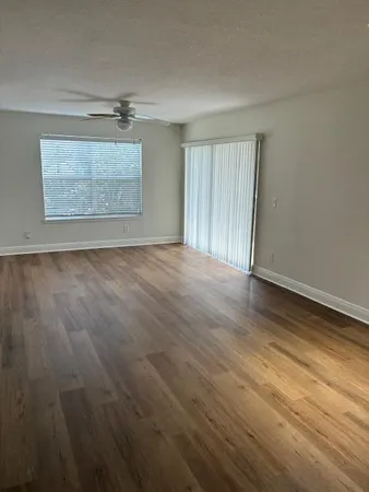 an empty room with wooden floor cabinet and windows