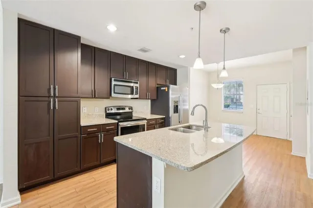 a kitchen with kitchen island a sink stainless steel appliances and wooden floor