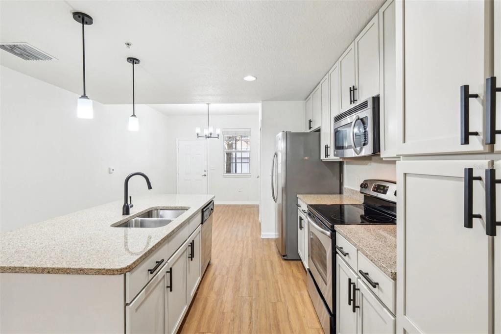 3334 South Bismark Lane, Unit 1B01304 Jupiter, FL 33458 - Photo 3 of 36 a kitchen with stainless steel appliances granite countertop a sink stove and refrigerator