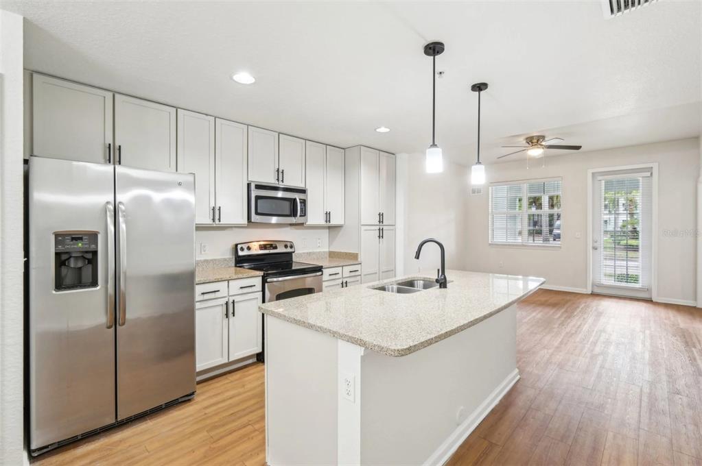 3334 South Bismark Lane, Unit 1B01304 Jupiter, FL 33458 - Photo 4 of 36 a kitchen with stainless steel appliances granite countertop a refrigerator a sink dishwasher a stove with wooden floor and cabinets