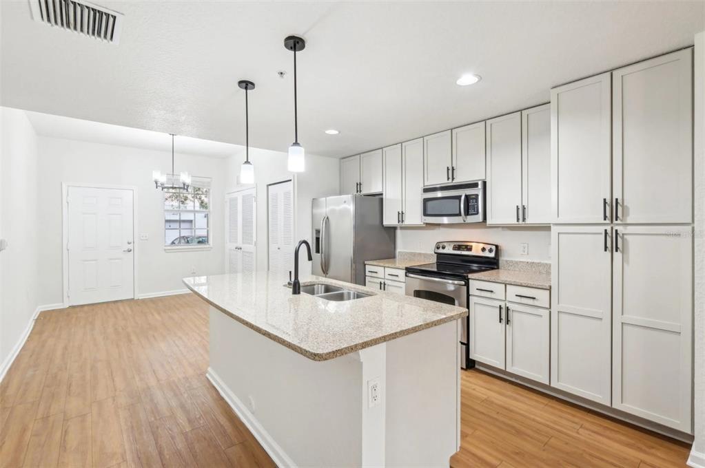 3334 South Bismark Lane, Unit 1B01304 Jupiter, FL 33458 - Photo 5 of 36 a kitchen with kitchen island a sink appliances and cabinets