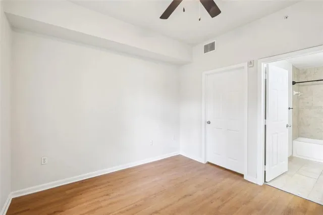 a view of an empty room with wooden floor and a ceiling fan