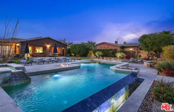 a view of a swimming pool with lawn chairs under an umbrella