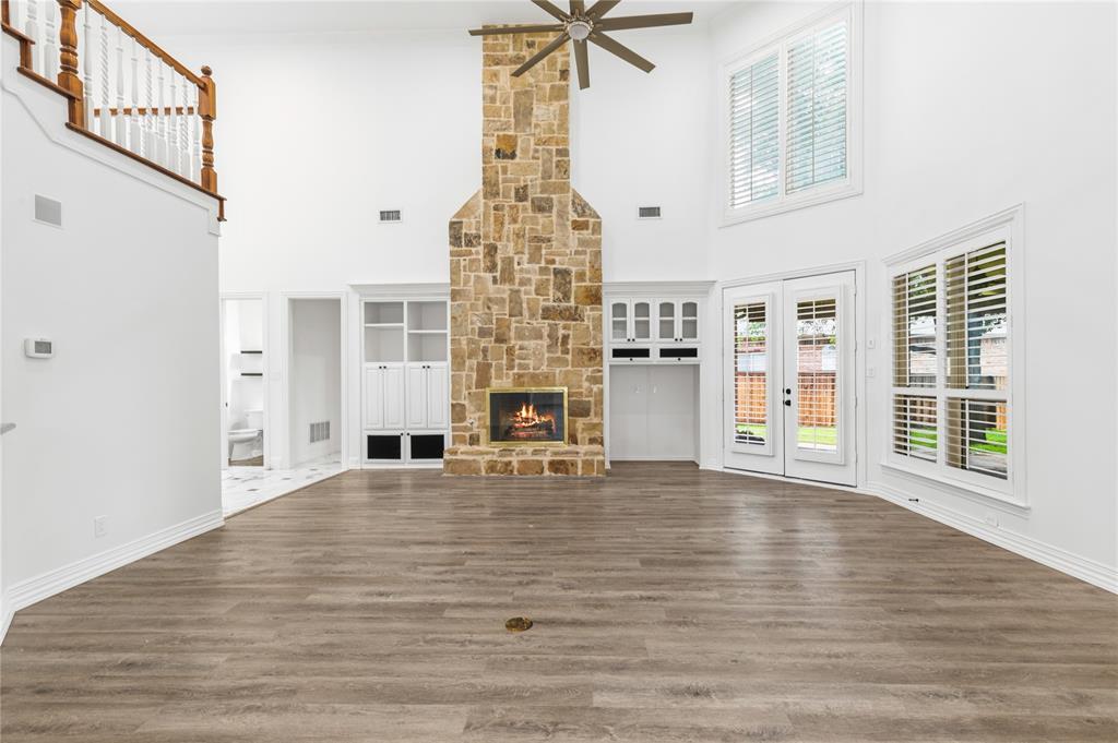 967 East Bethel School Road Coppell, TX 75019 - Photo 18 of 39 Spacious living area featuring wood-finish flooring, a stone-clad fireplace, and high ceilings